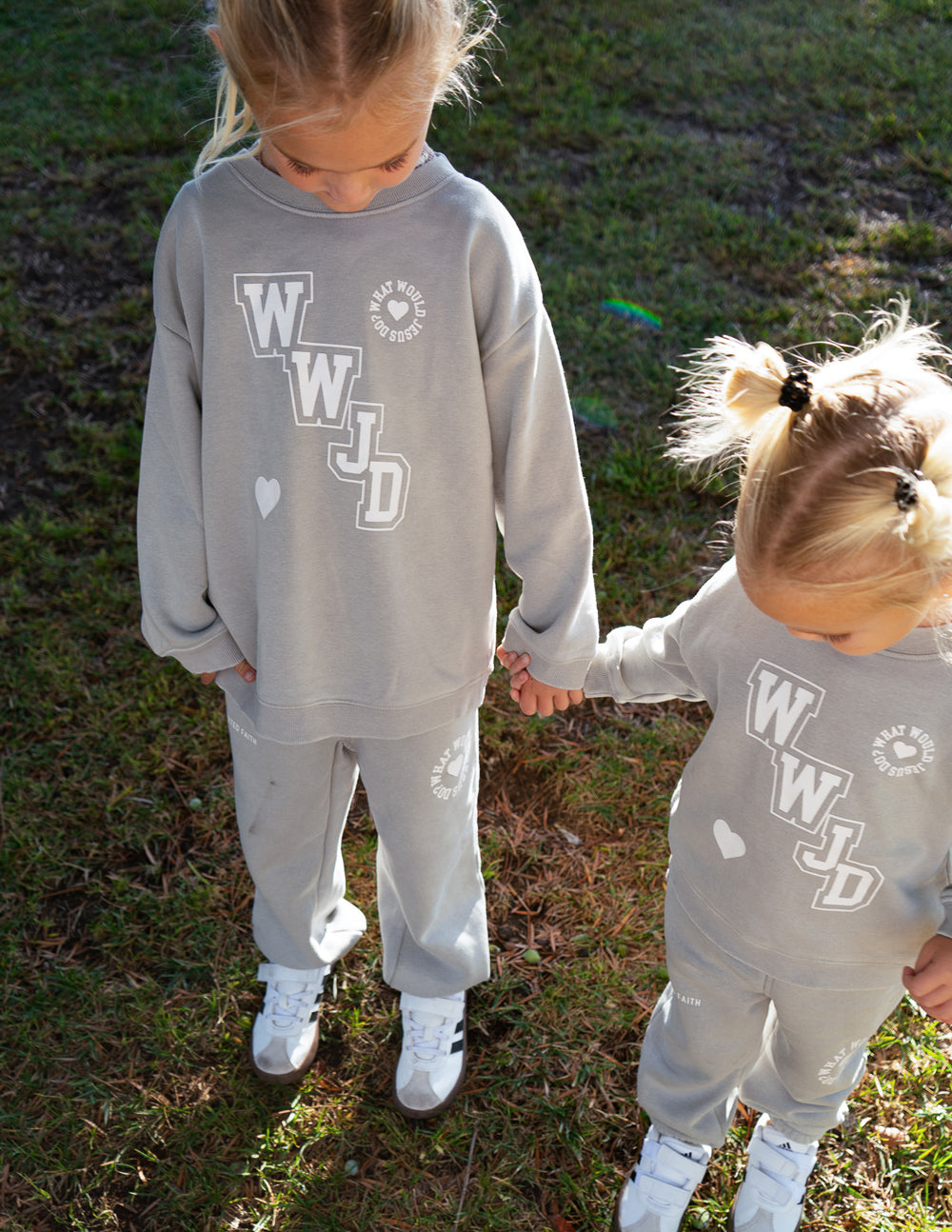 Kids varsity crewneck sweatshirt in light gray with WJD front logo and heart