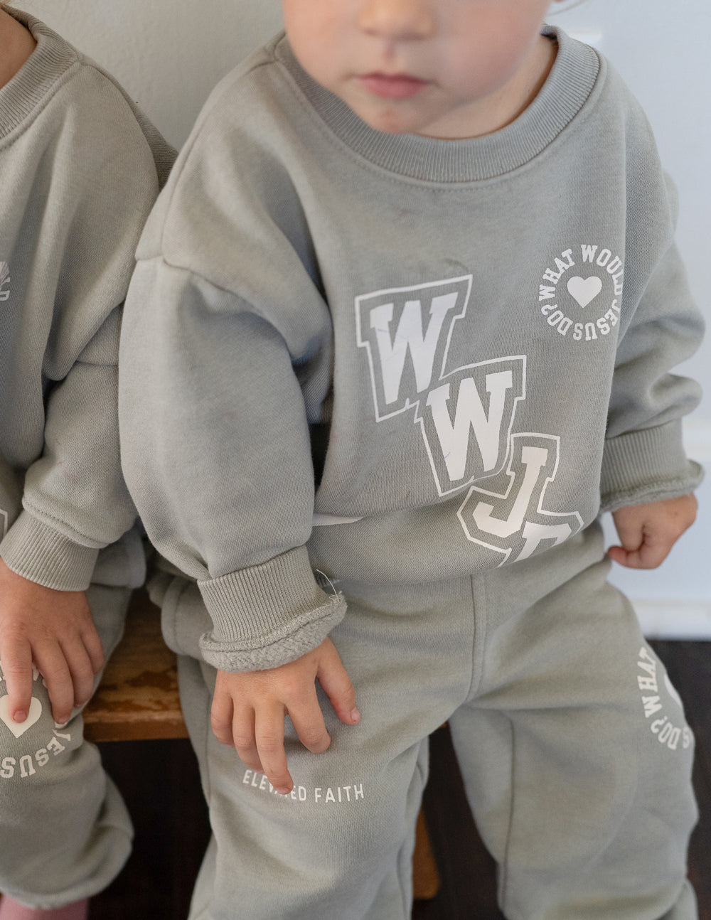 Kids varsity crewneck sweatshirt close-up in light gray with WJD front graphic