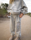 Light gray kids sweatpants with elastic cuffs and waistband, printed heart logo