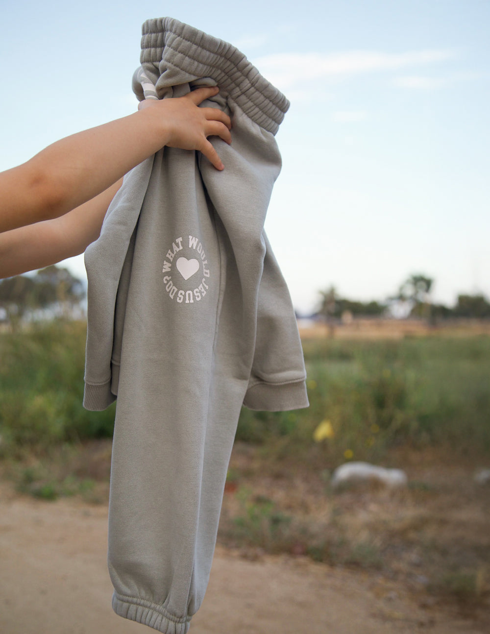 Light gray kids sweatpants with front pocket openings and heart logo print