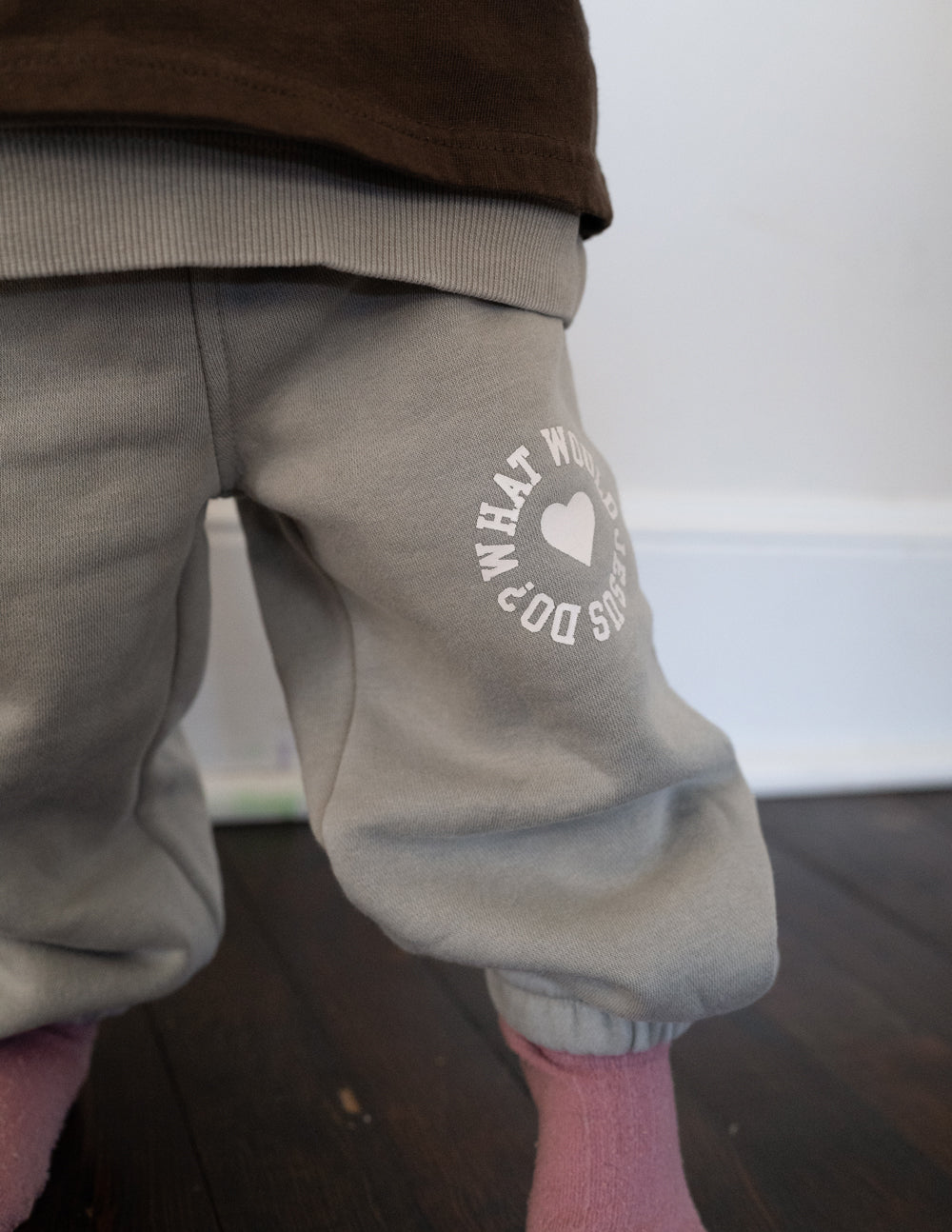 Light gray kids sweatpants with heart graphic on the knee and gathered cuff