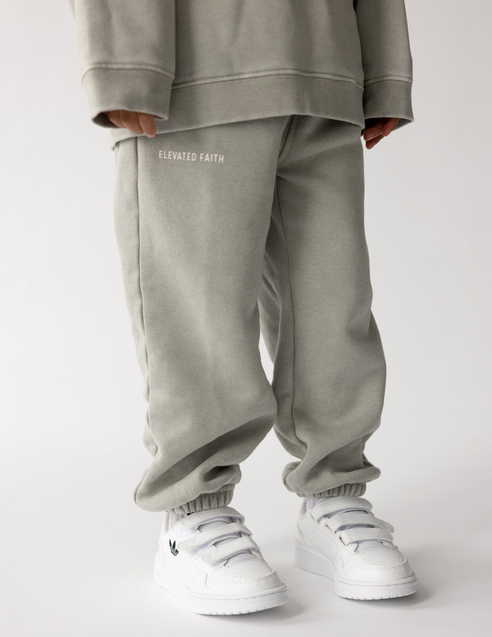 Light gray kids sweatpants with back logo text, elastic cuffs and relaxed fit