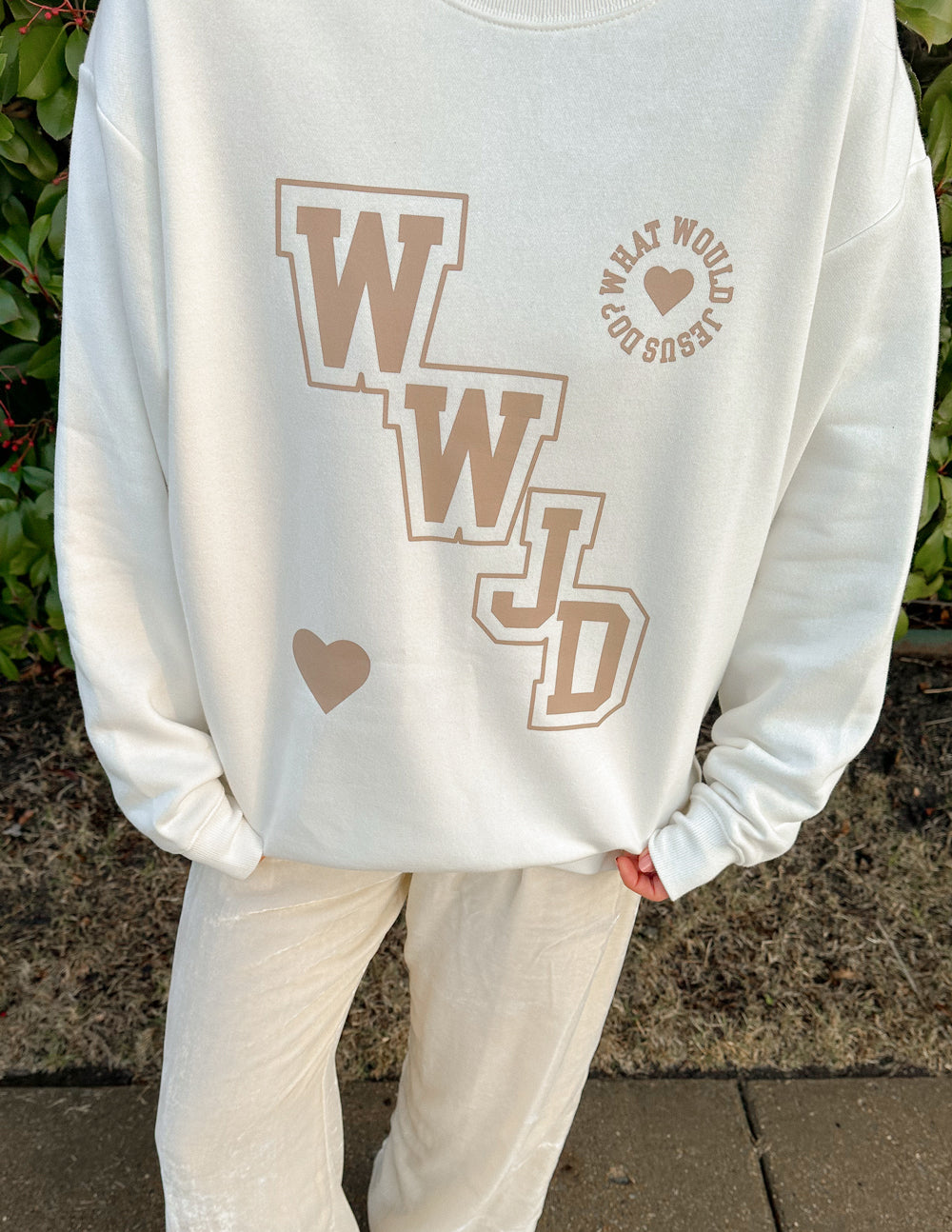 Off-white crewneck sweatshirt close-up: WWJD varsity logo, heart, and text badge