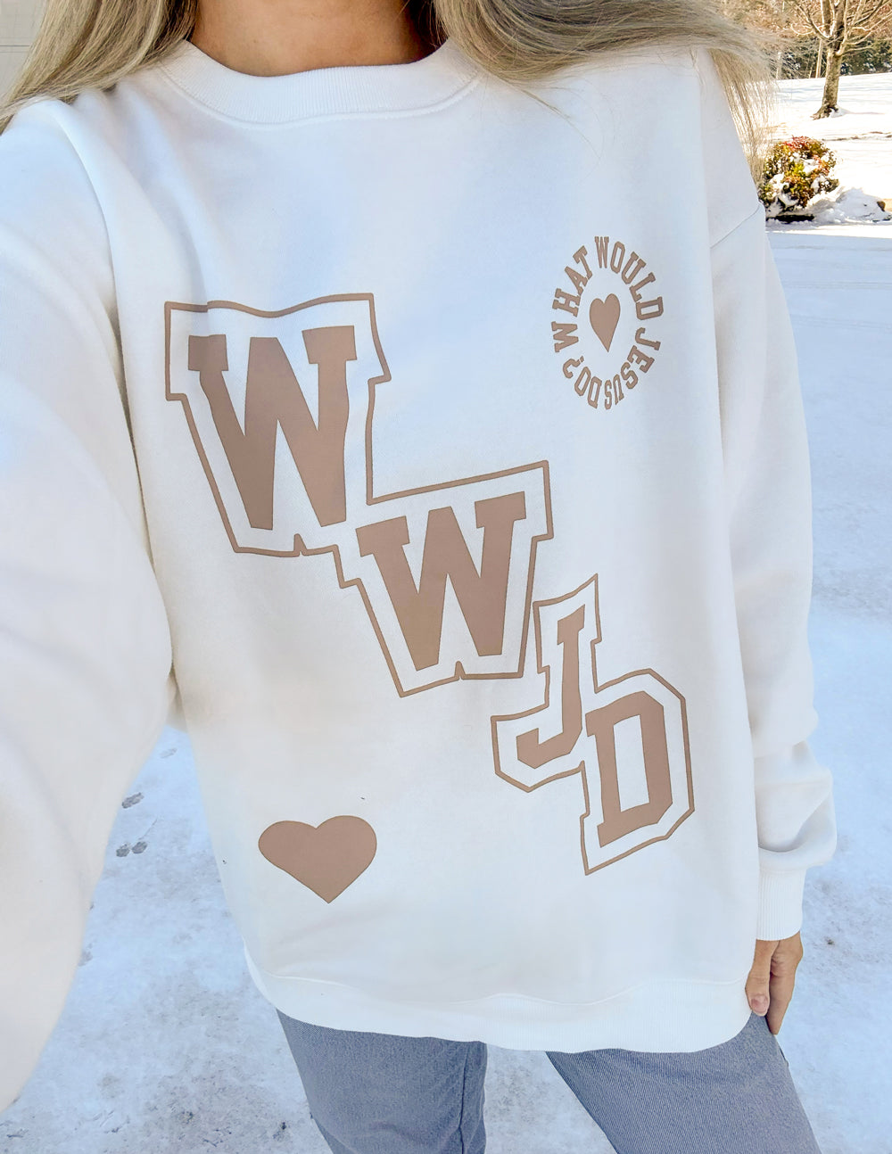 Off-white crewneck sweatshirt close-up with WWJD varsity graphic and heart