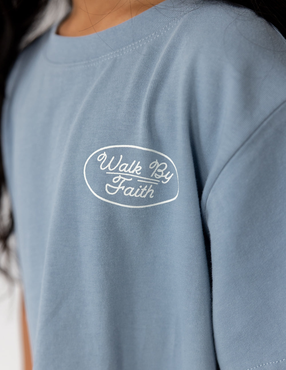 Light blue kids T-shirt with small circular "Walk By Faith" chest logo