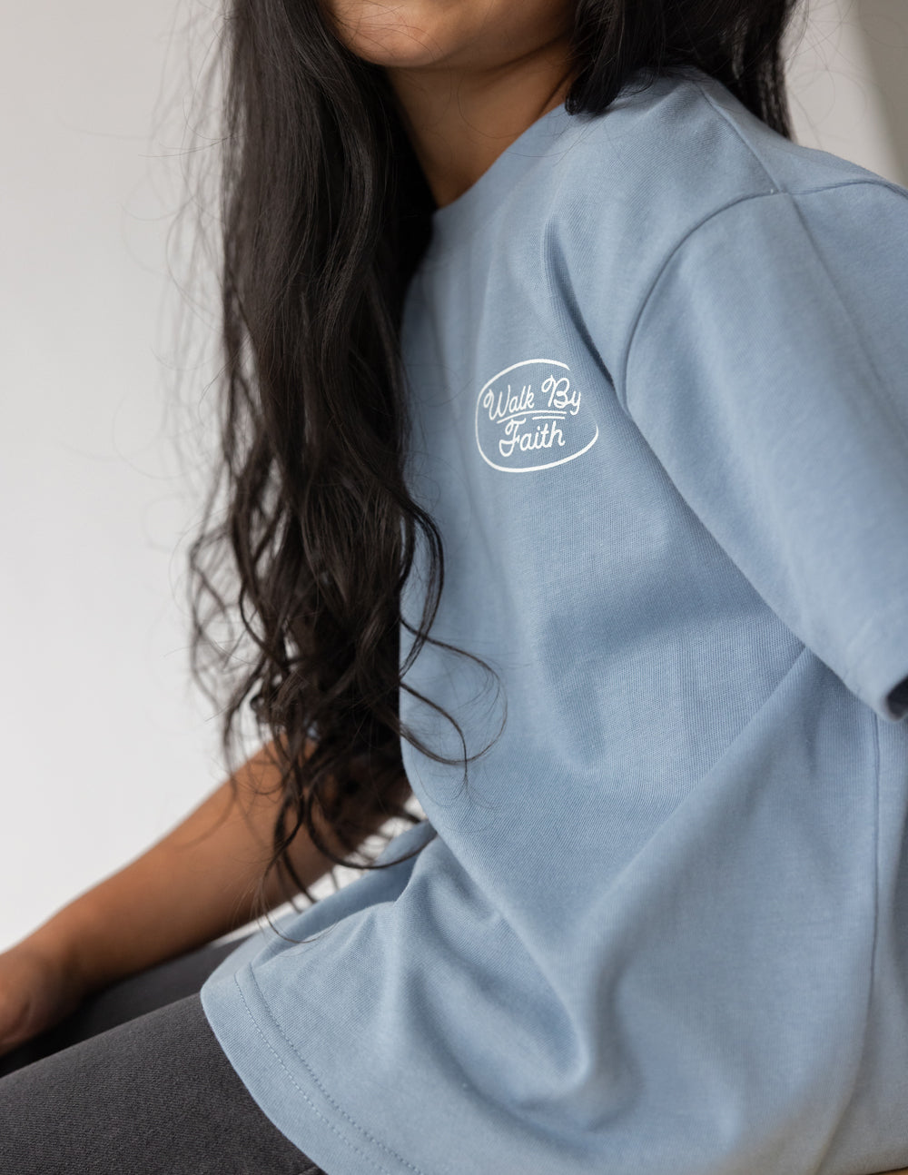 Light blue kids T-shirt with small oval "Walk By Faith" logo near the chest