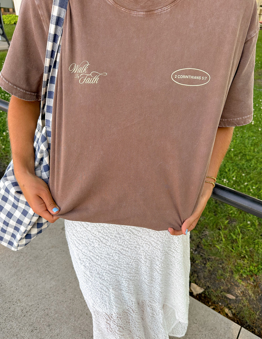 Brown crewneck tee with 'Walk by Faith' script and '2 Corinthians 5:7' oval chest print.