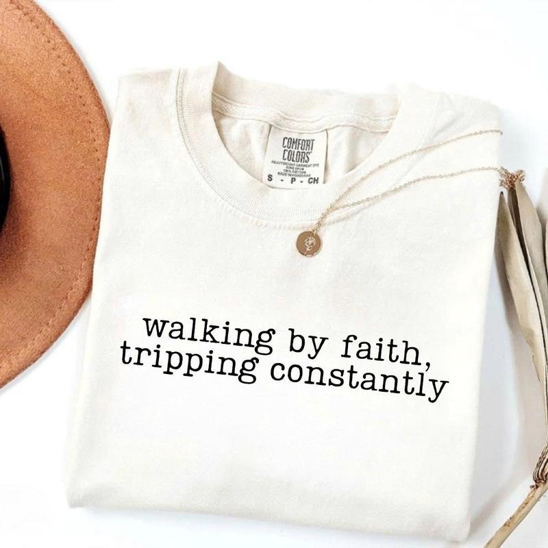 Women’s crewneck graphic tee, white with “walking by faith, tripping constantly”