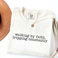Women’s crewneck graphic tee, white with “walking by faith, tripping constantly”