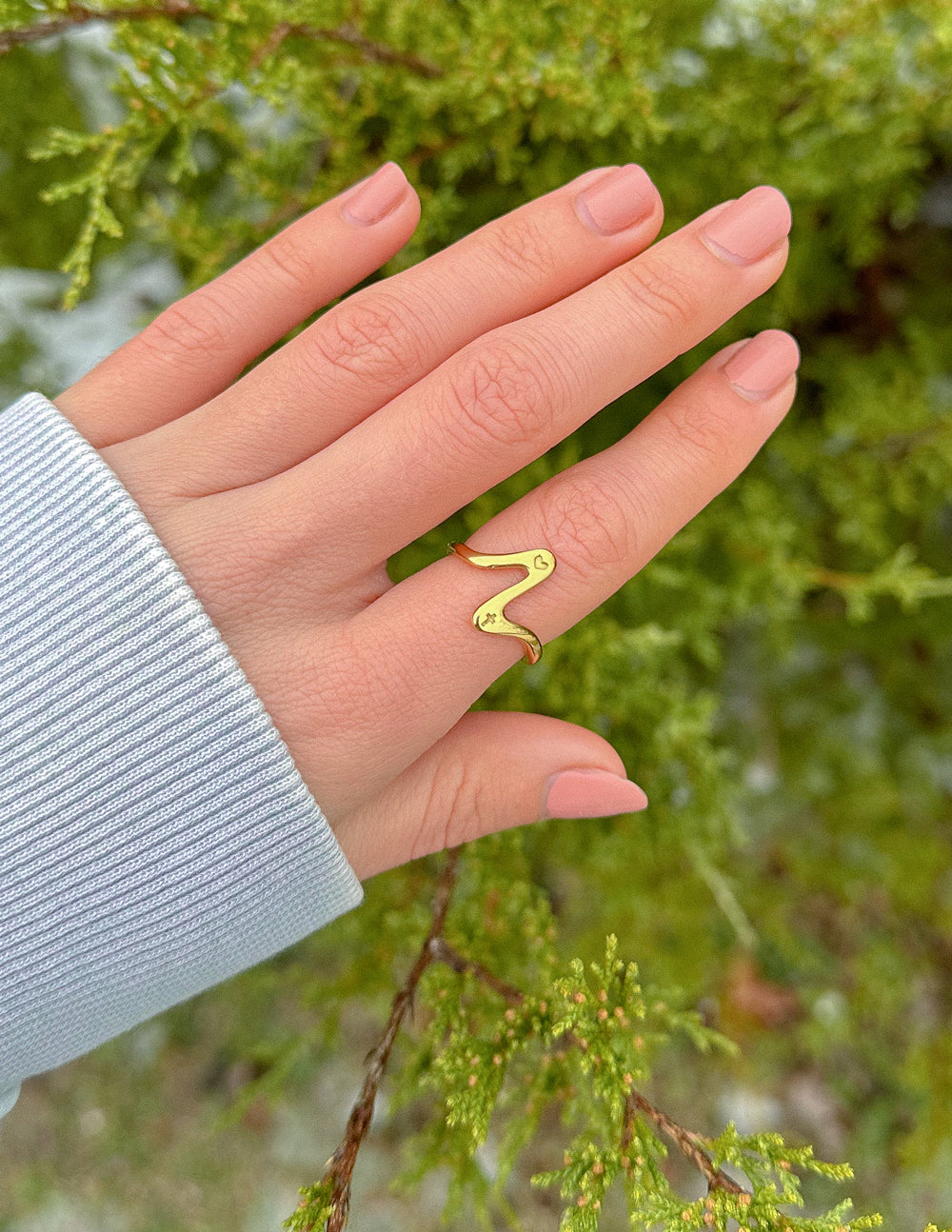 Gold wavy heart ring on finger, open heart outline and heart accents