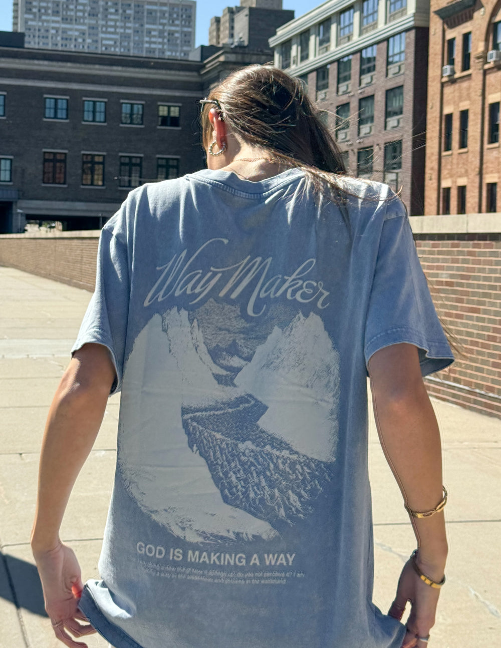 Unisex blue Way Maker T-shirt back view with mountain graphic and “God is making a way”.