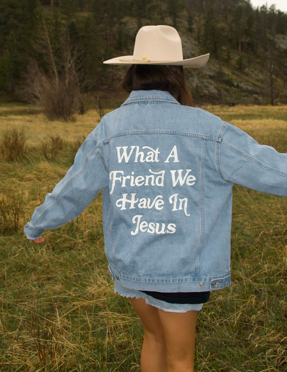 Light-wash denim jacket with large back graphic text and long sleeves