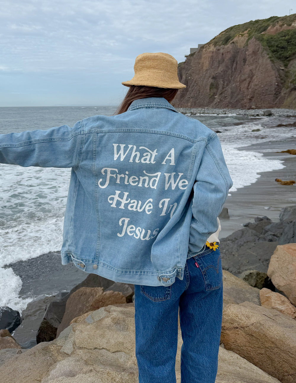 Light-wash denim jacket with large back graphic text and button front