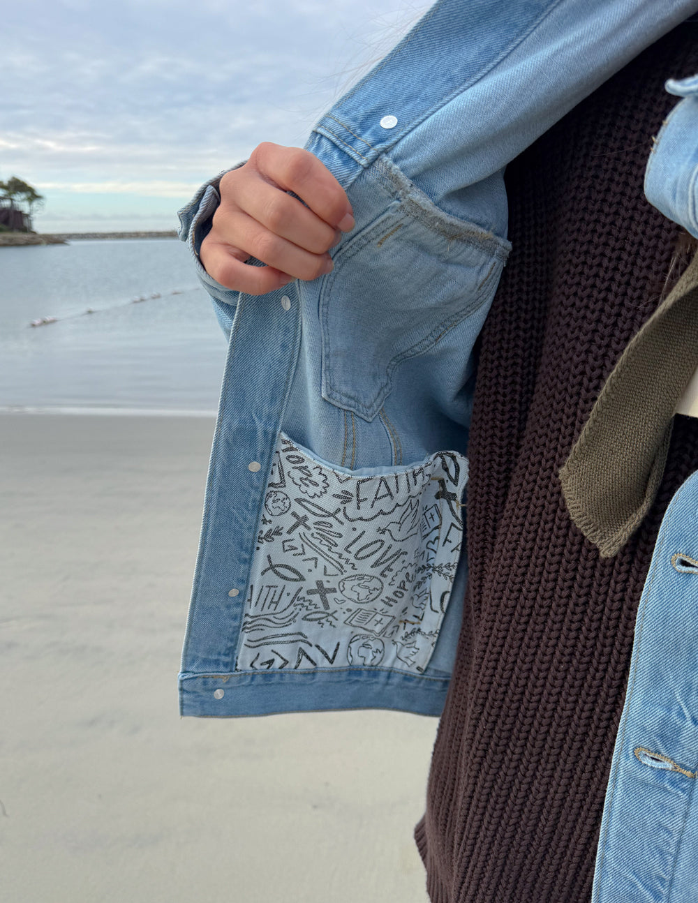 Light-wash denim jacket sleeve pocket and button placket with inner graphic patch