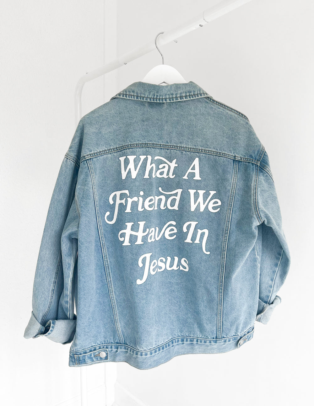 Light blue denim jacket with 'What A Friend We Have In Jesus' back graphic on hanger