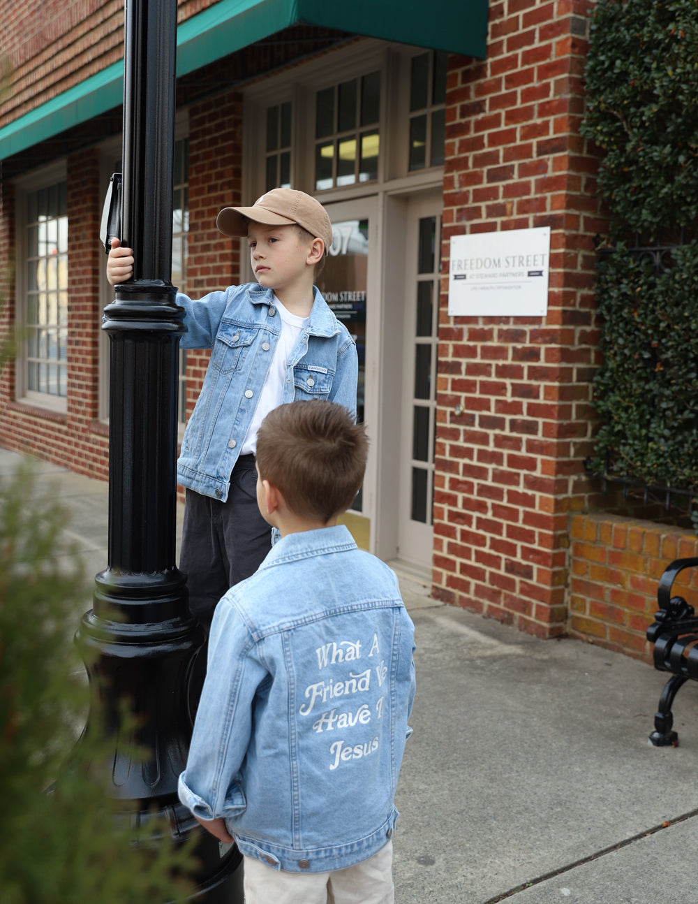 Kids light-wash denim jacket with back inspirational text print mentioning Jesus