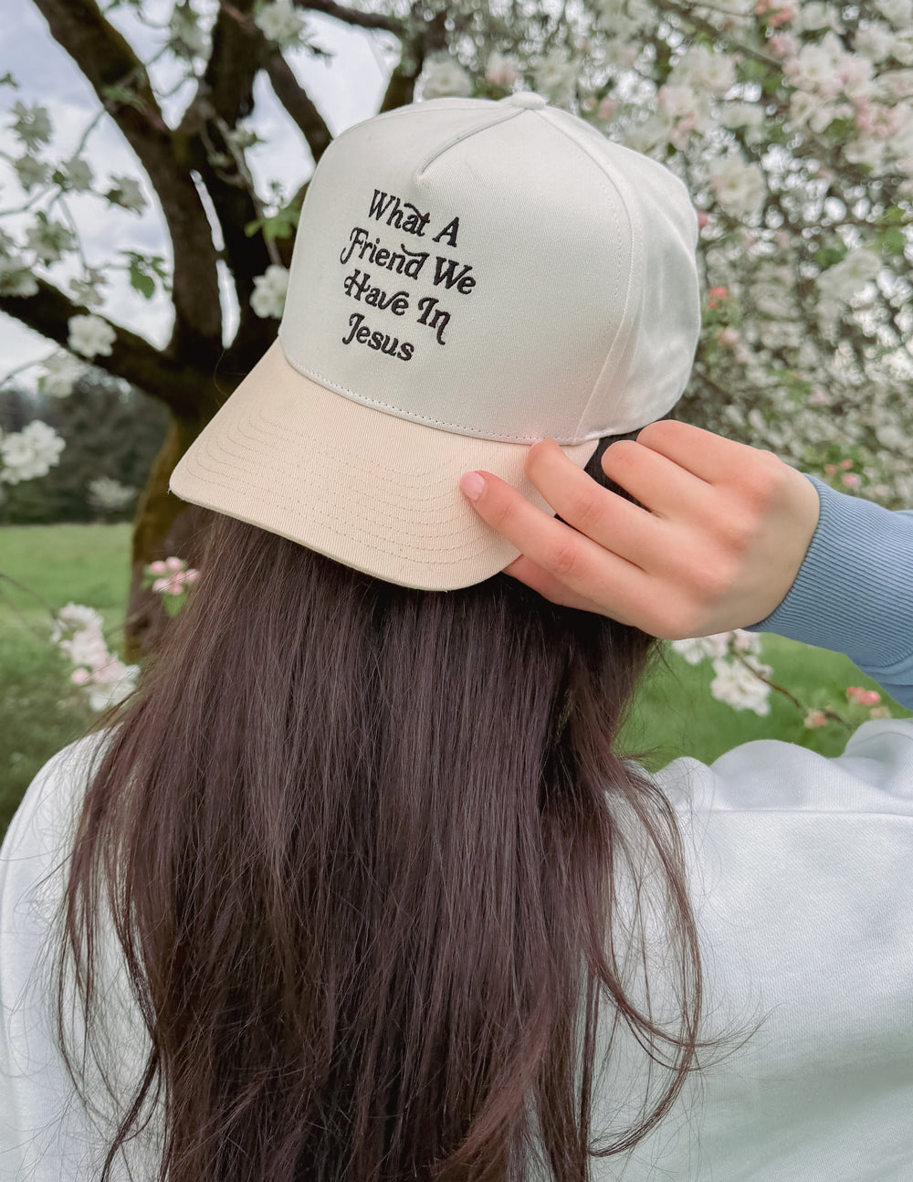White cap worn outdoors, with “What a Friend We Have In Jesus” front embroidery