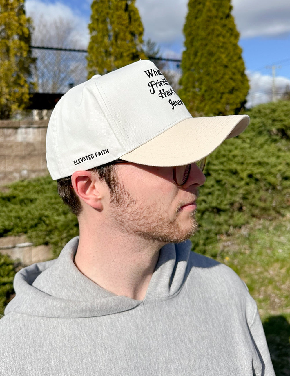 White and beige trucker hat with embroidered religious text on the front