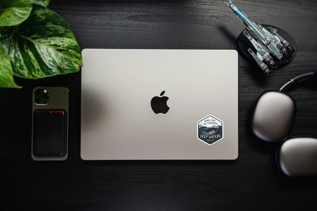Laptop with small hex Christian sticker showing ocean waves and Isaiah 43:2.