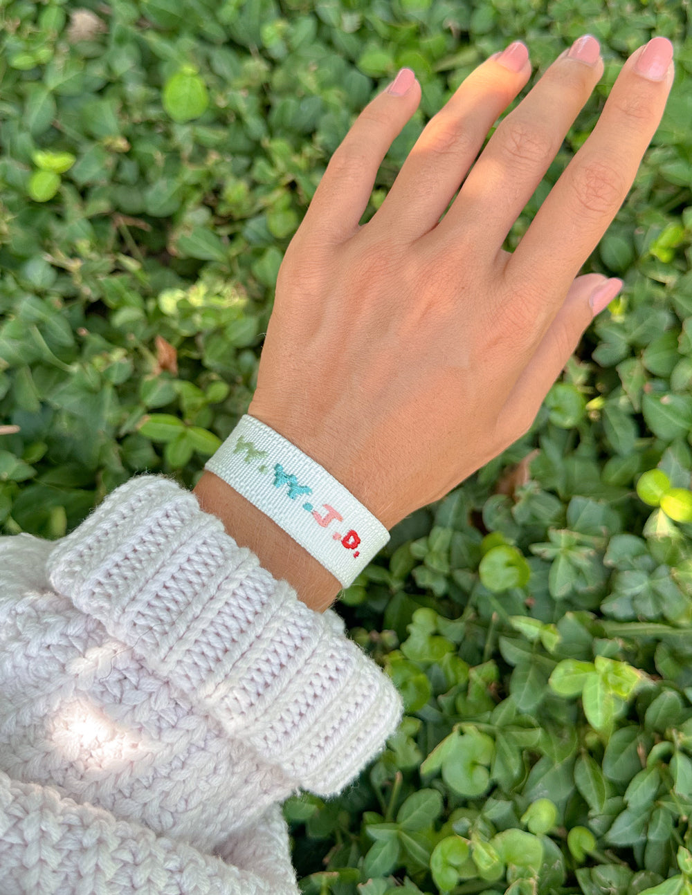 White woven bracelet with turquoise and red embroidered pattern on wrist