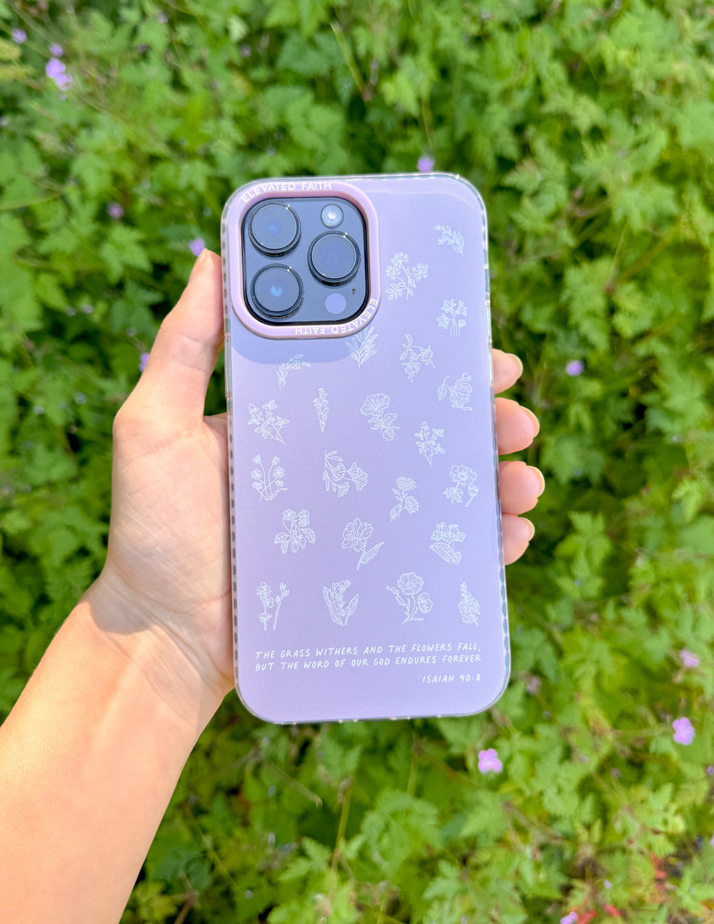 Lavender phone case with white wildflower pattern, held in hand outdoors