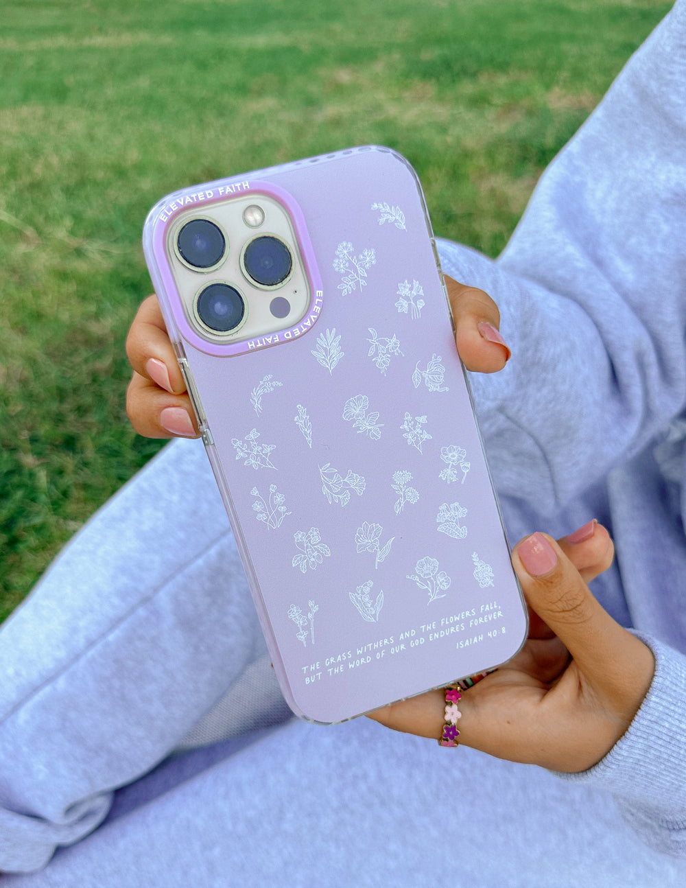 Lavender phone case with white wildflower pattern on phone, outdoors