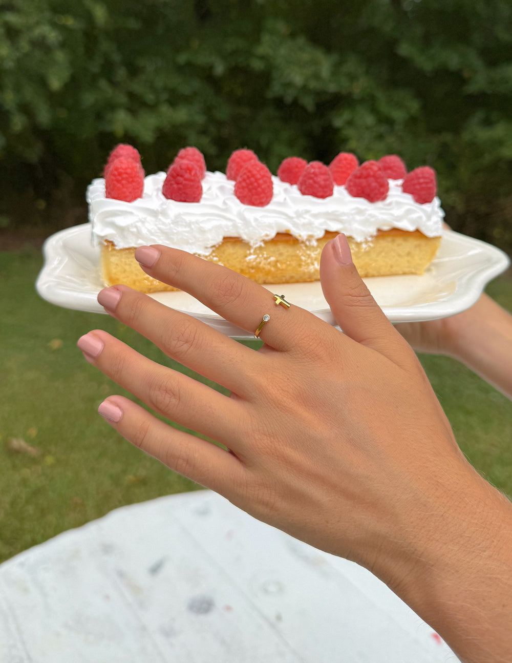 Gold cross ring with small gem, worn on finger