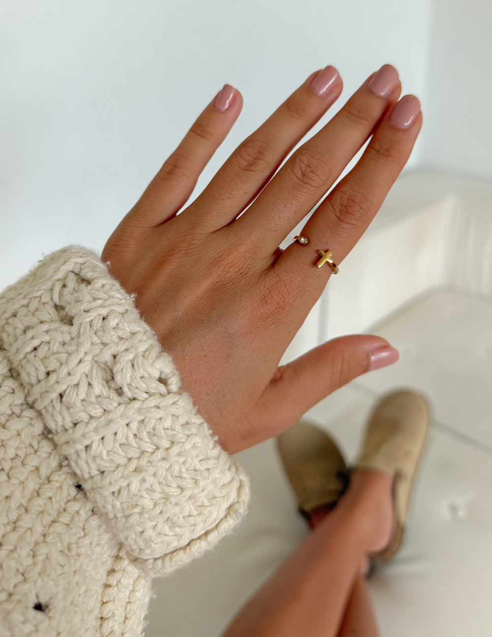 Gold cross ring with gem detail, worn on hand