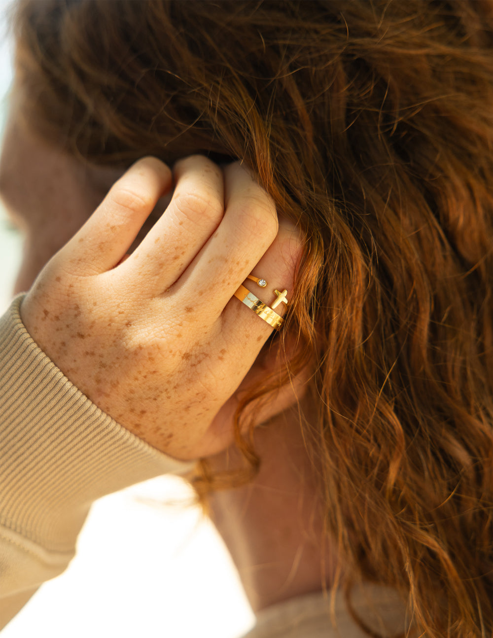 Gold cross ring with gem detail, worn on finger