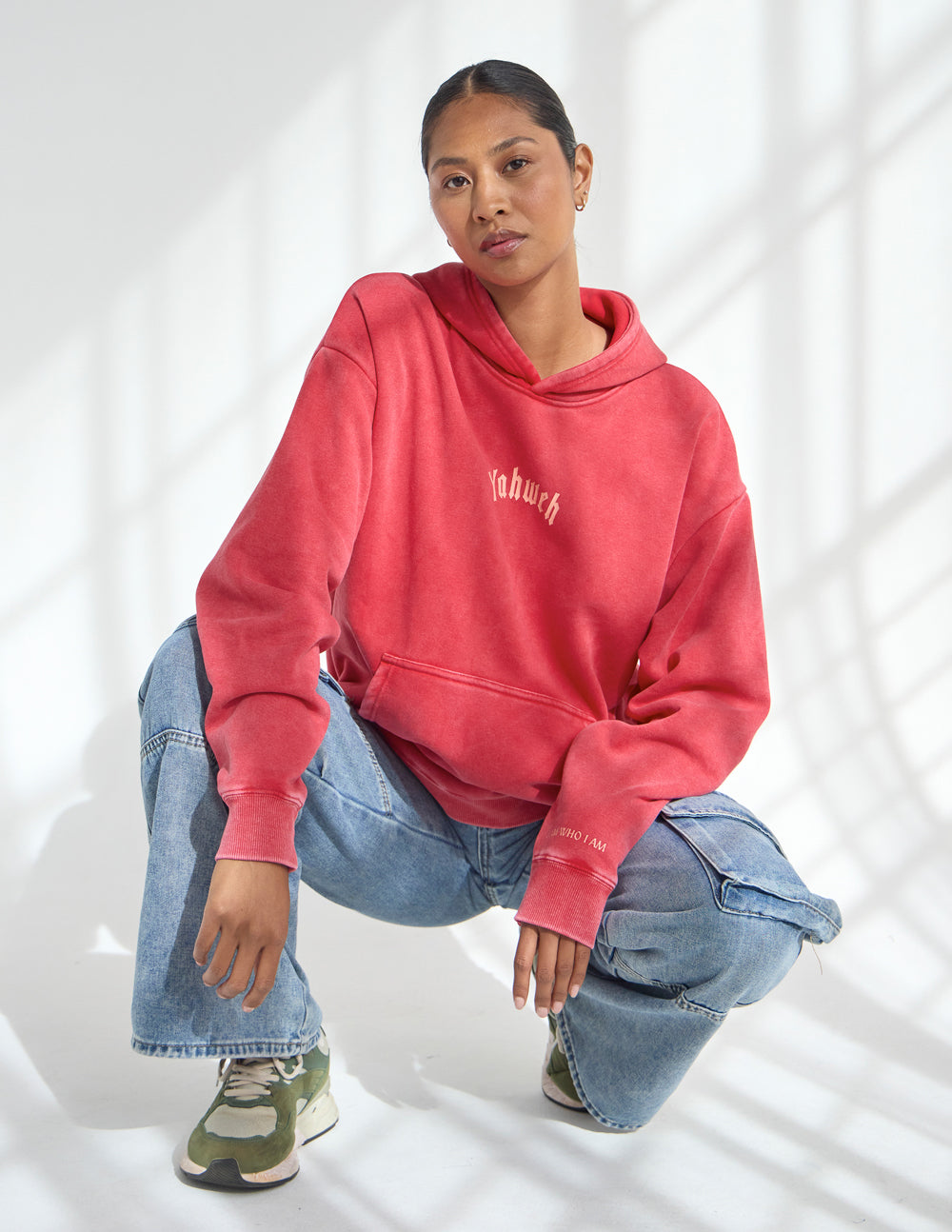 Red unisex hoodie with hood and chest logo, loose long sleeves.
