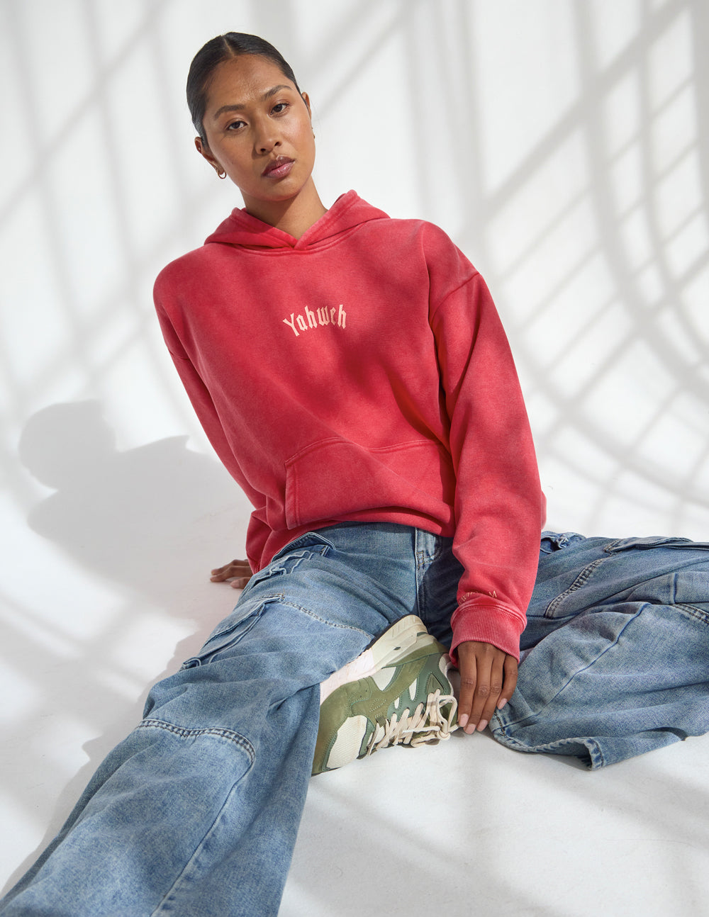 Red unisex hoodie with hood and chest logo, dropped-shoulder fit.