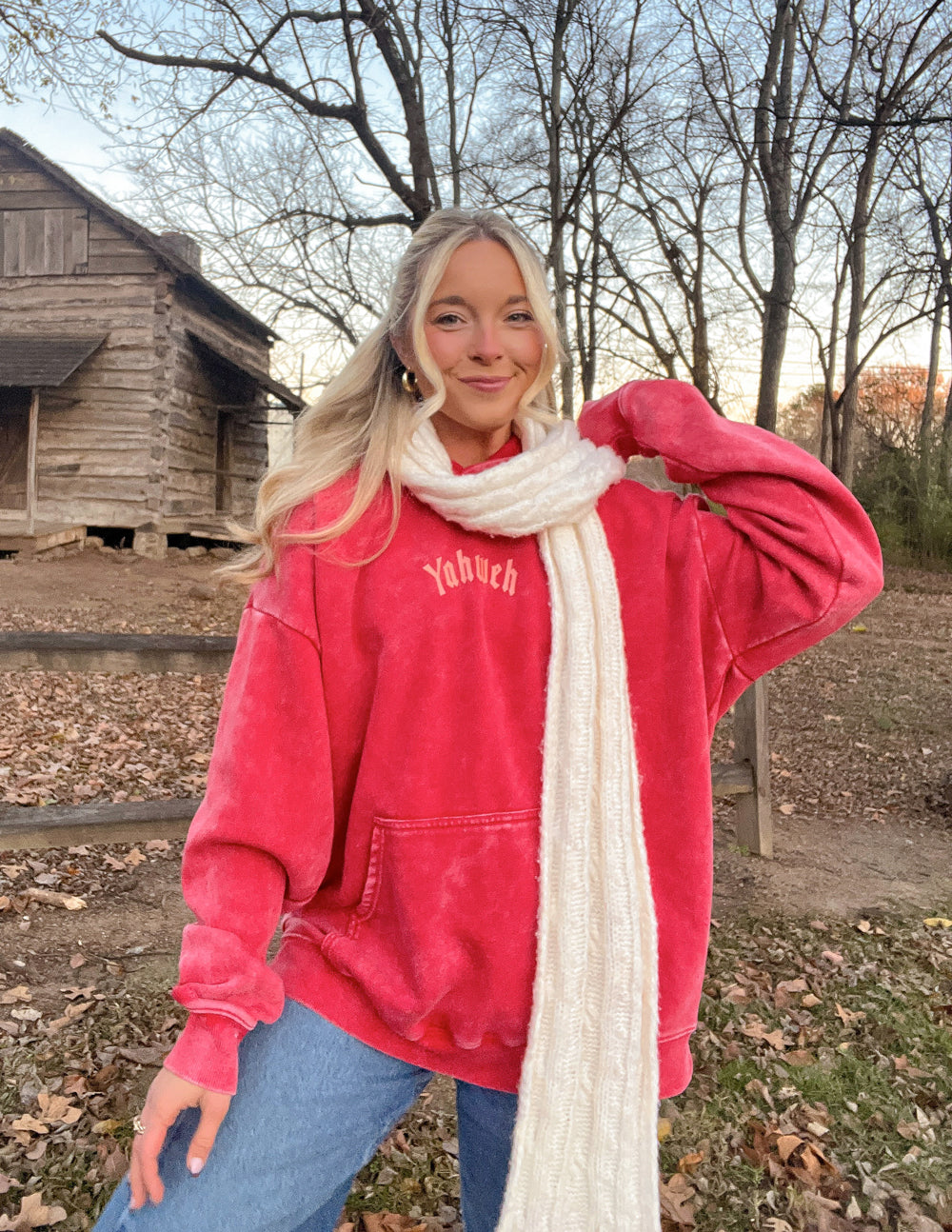 Red unisex hoodie with chest logo, worn with white knit scarf.