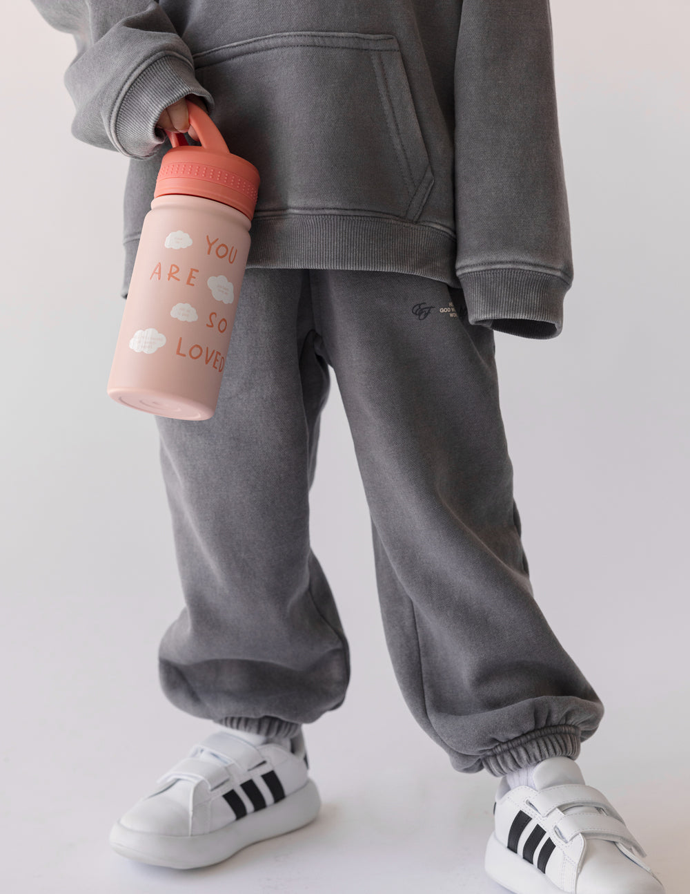 Pink kids water bottle with orange flip-top lid, shown in side view.