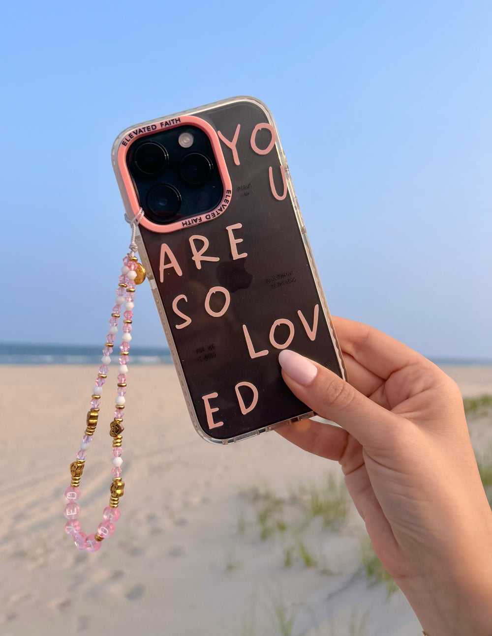 Beaded phone charm hanging from phone case, pink beads with gold connector pieces