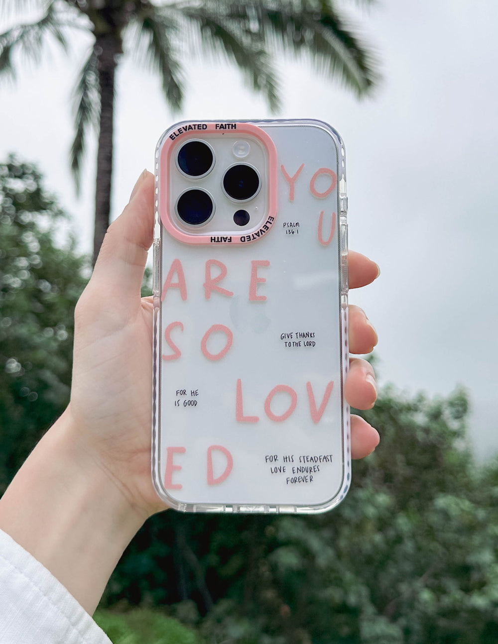 Clear phone case with pink lettering and four camera cutouts, held up for view
