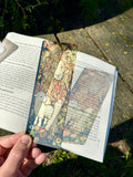 Colorful portrait bookmark with lion-and-lamb illustration, placed in an open book
