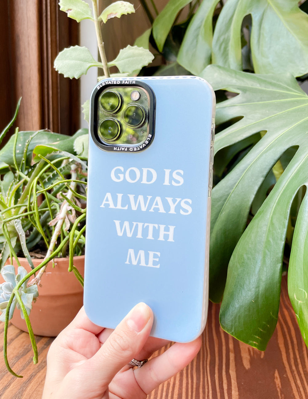 Light blue phone case with 'GOD IS ALWAYS WITH ME' and triple-lens camera cutout