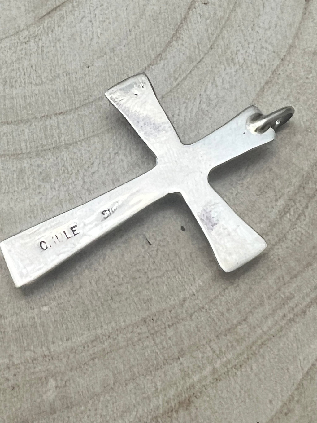 Silver-tone cross pendant back with stamp "C. IULE" and hanging loop.