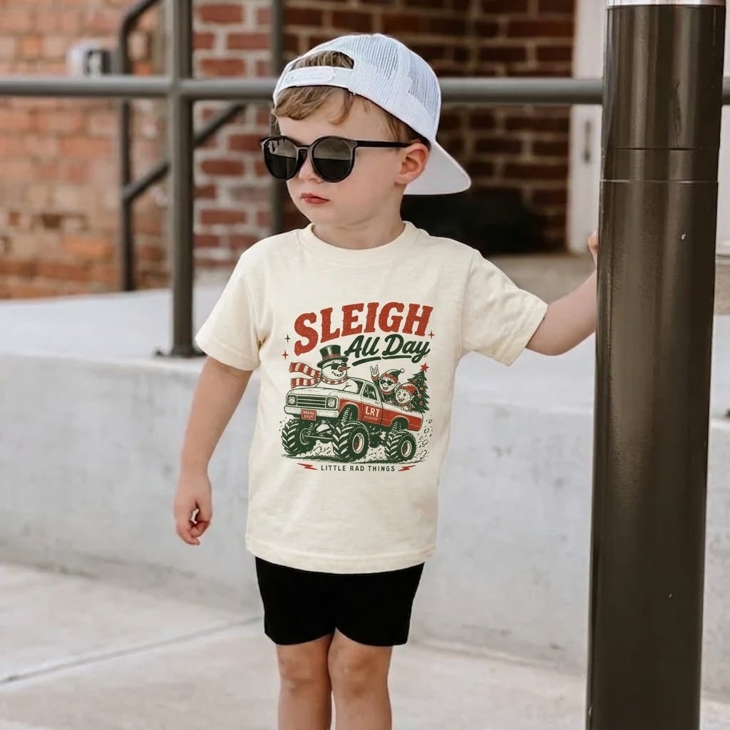 Ivory toddler Christmas t-shirt with “Sleigh All Day” monster truck front graphic