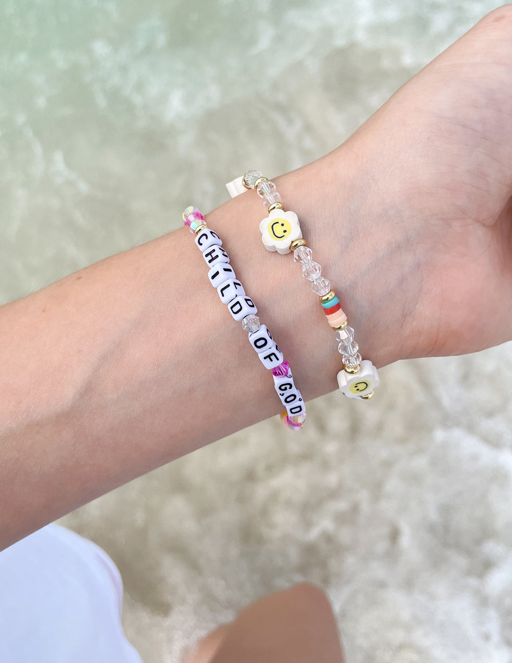 Child of God letter bracelet on wrist with multicolor beads and heart charms