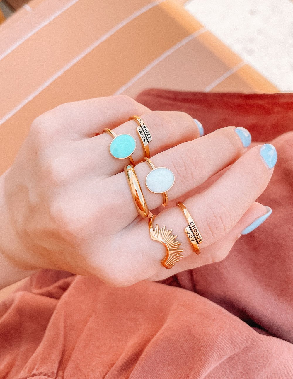Gold ring with black 'CHOOSE JOY' lettering on the band, worn on finger