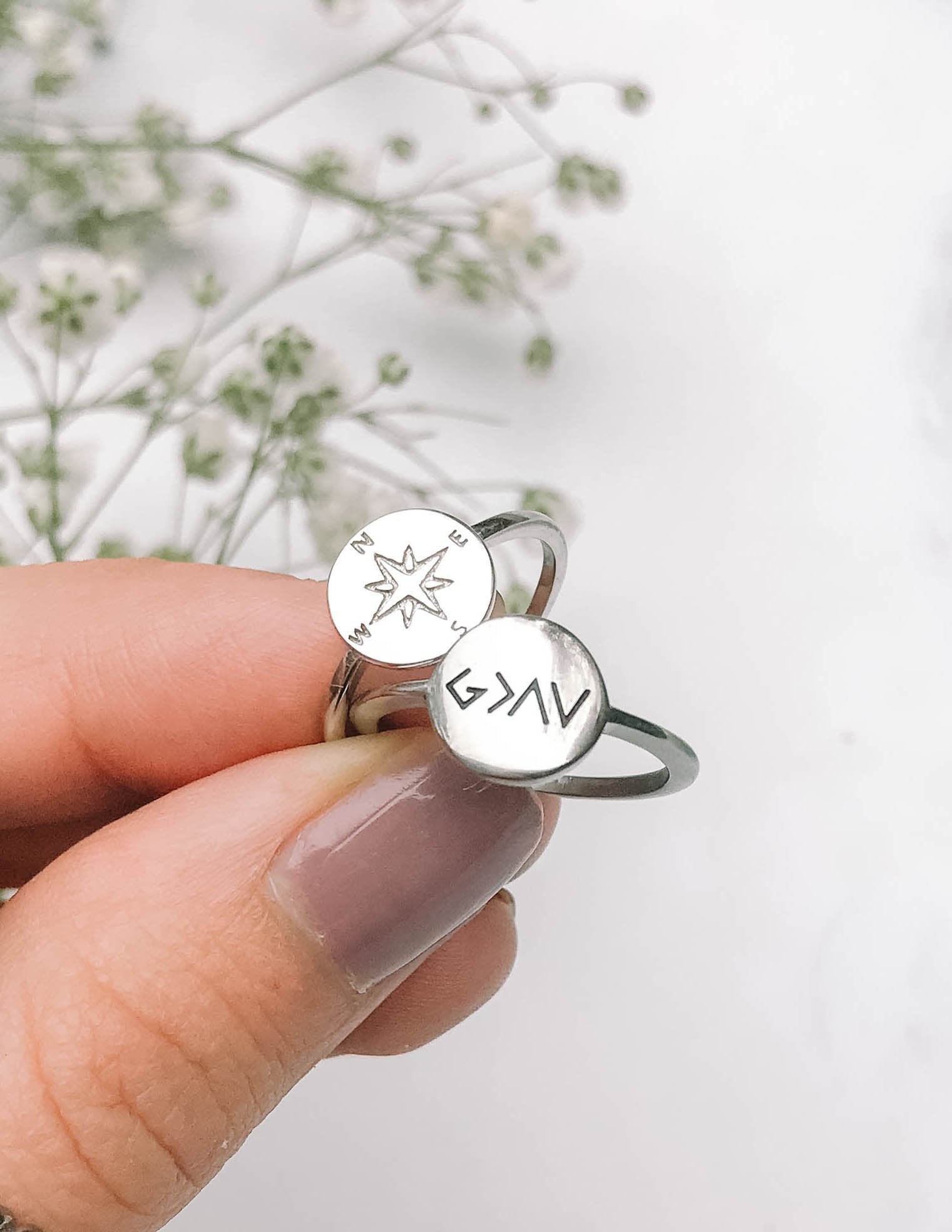 Silver compass-style ring with star dial, worn on finger