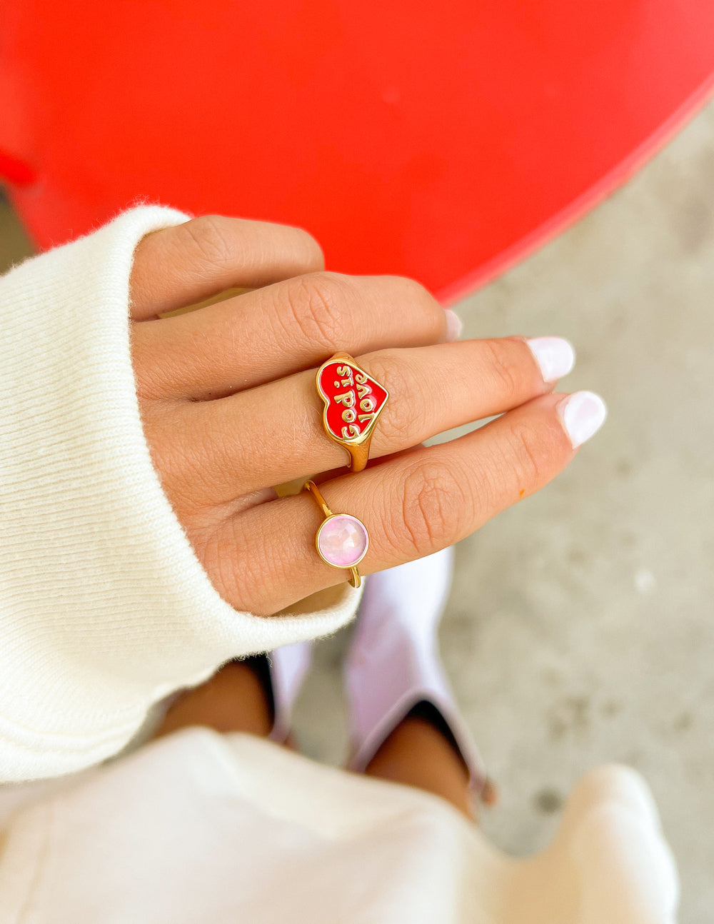 Gold-tone enamel heart ring with red “God is Love” lettering, worn on finger