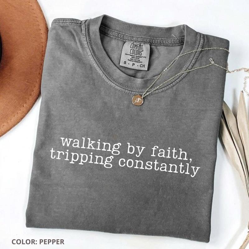 Women’s crewneck graphic tee, dark gray with “walking by faith, tripping constantly”