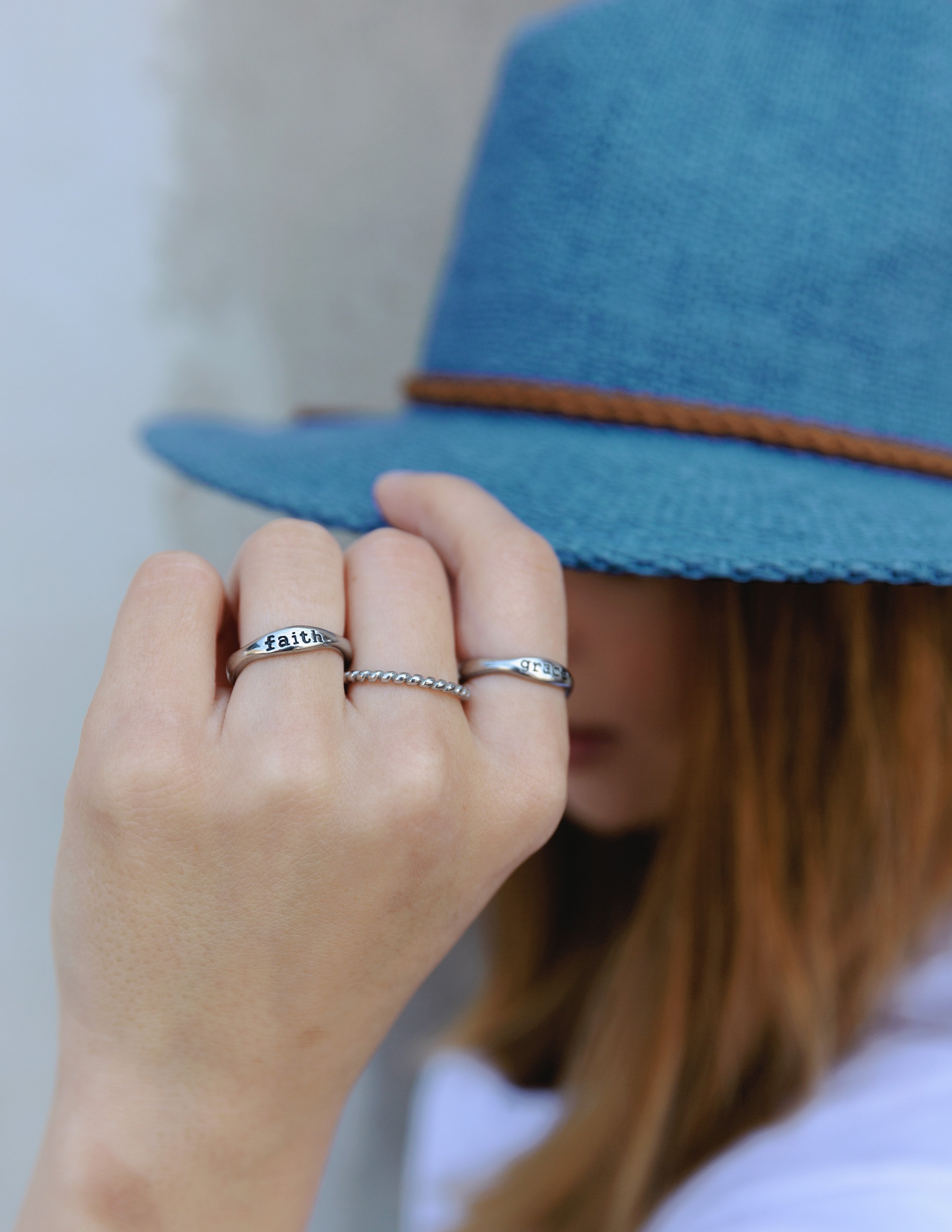 Silver 'faith' ring on a finger, shown in a close-up hand pose