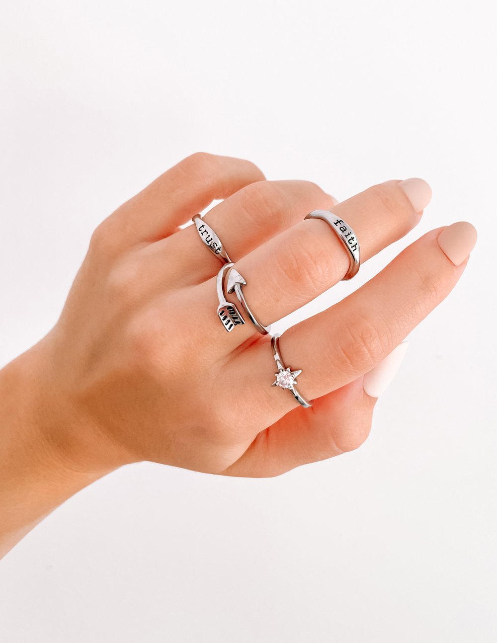 Silver stack rings on fingers, including 'faith' band and small star charm