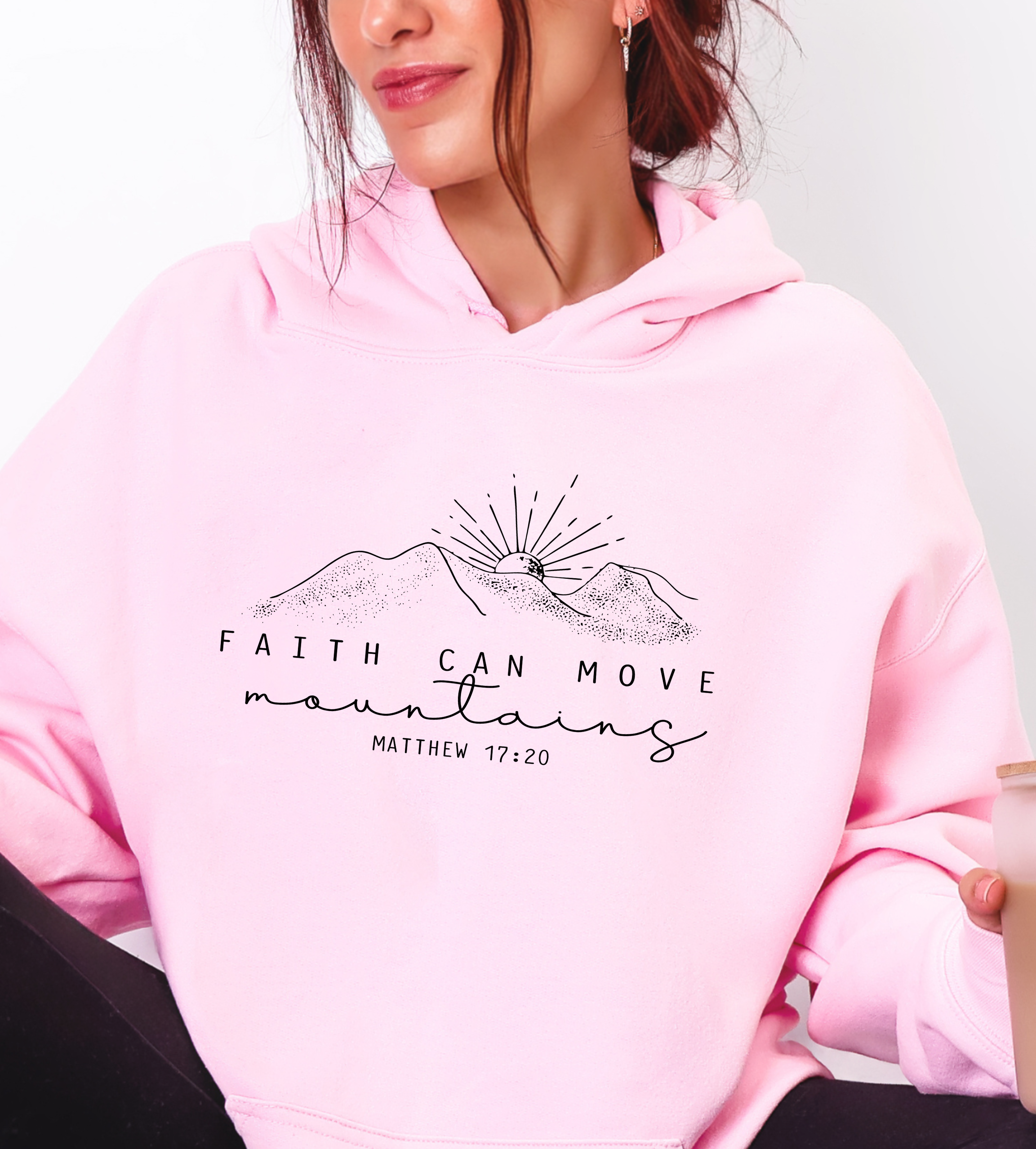 Pink hoodie with mountain sun graphic and Matthew 17:20 text