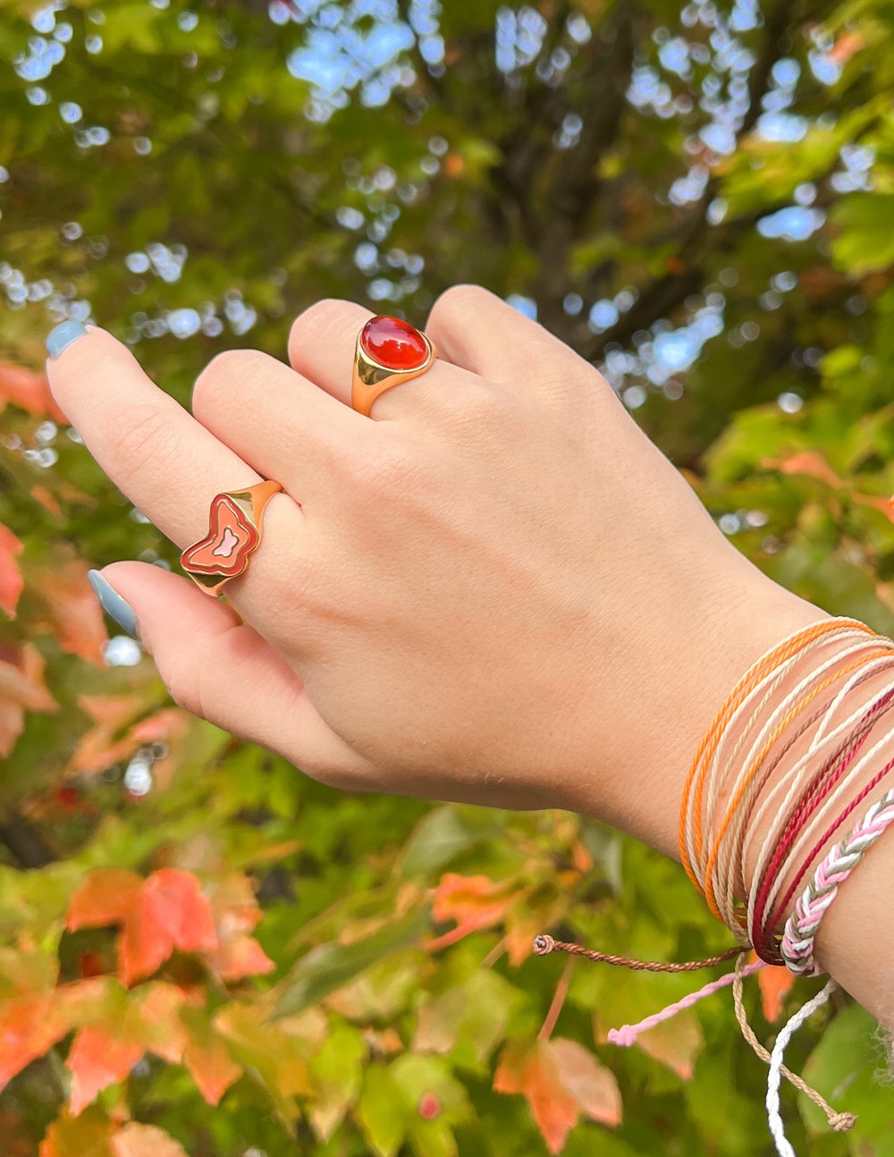 Gold-tone ring with red heart charm and red cabochon gemstone on finger