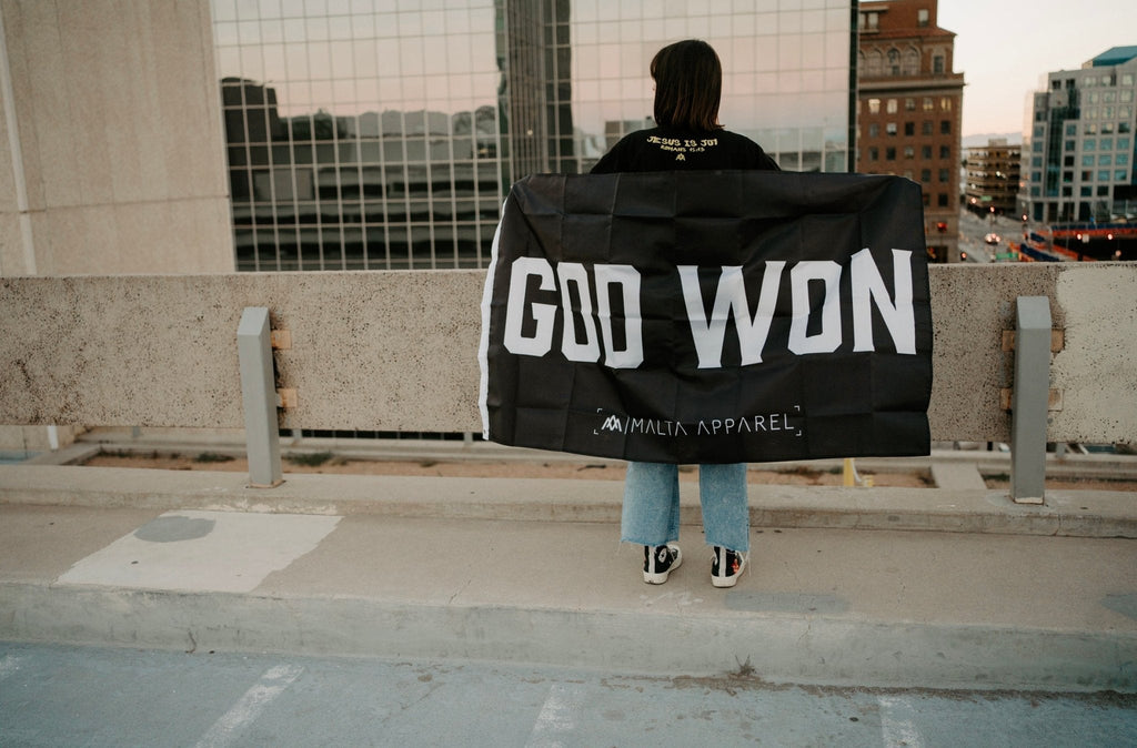 God Won flag-style wrap draped over shoulders, black with white 'GOD WON' text