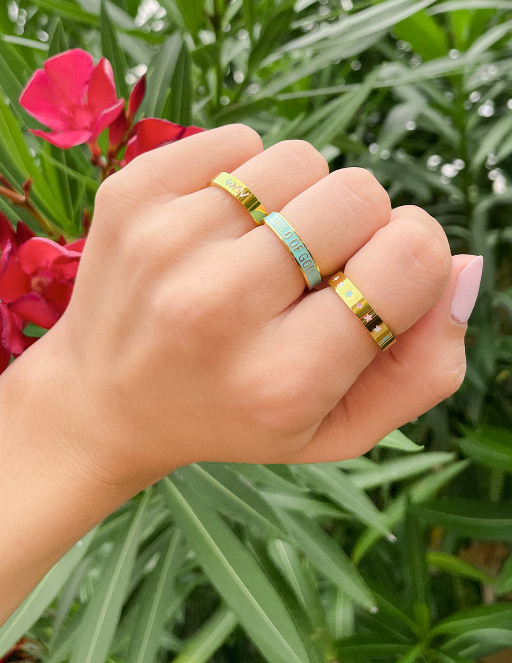 Gold enamel rings on hand with colored logo detail on band
